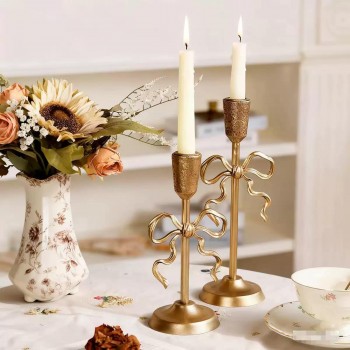 شمعدان ذهبي بتصميم الفيونكة لمسة من الرقي والشاعرية على منزلك، حيث يجمع بين الفخامة الكلاسيكية وجمال التفاصيل المنسوجة يدوياً متوفر الحجمين L9575
